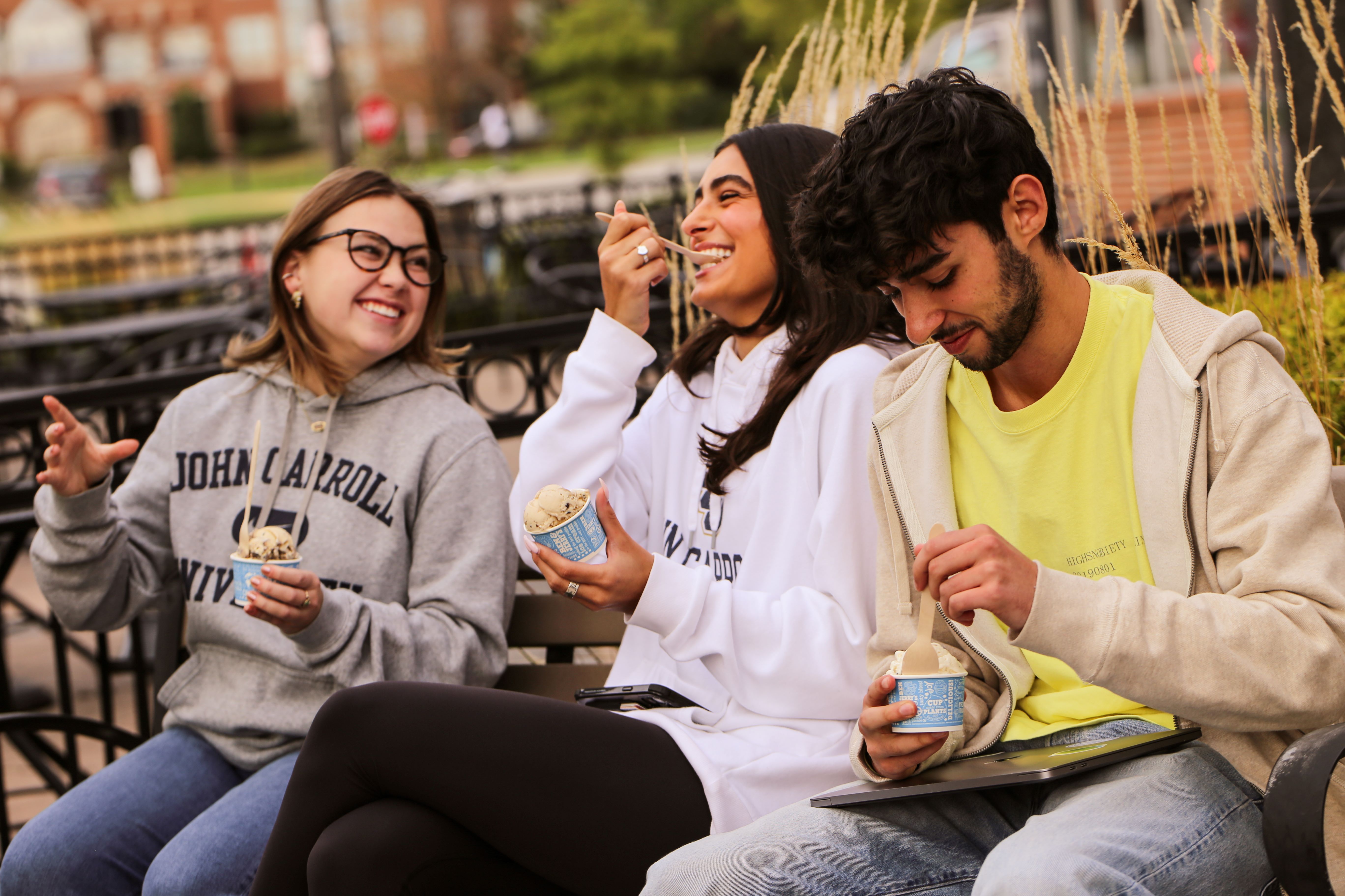 three students enjoying ice cream at a shop outside of campus