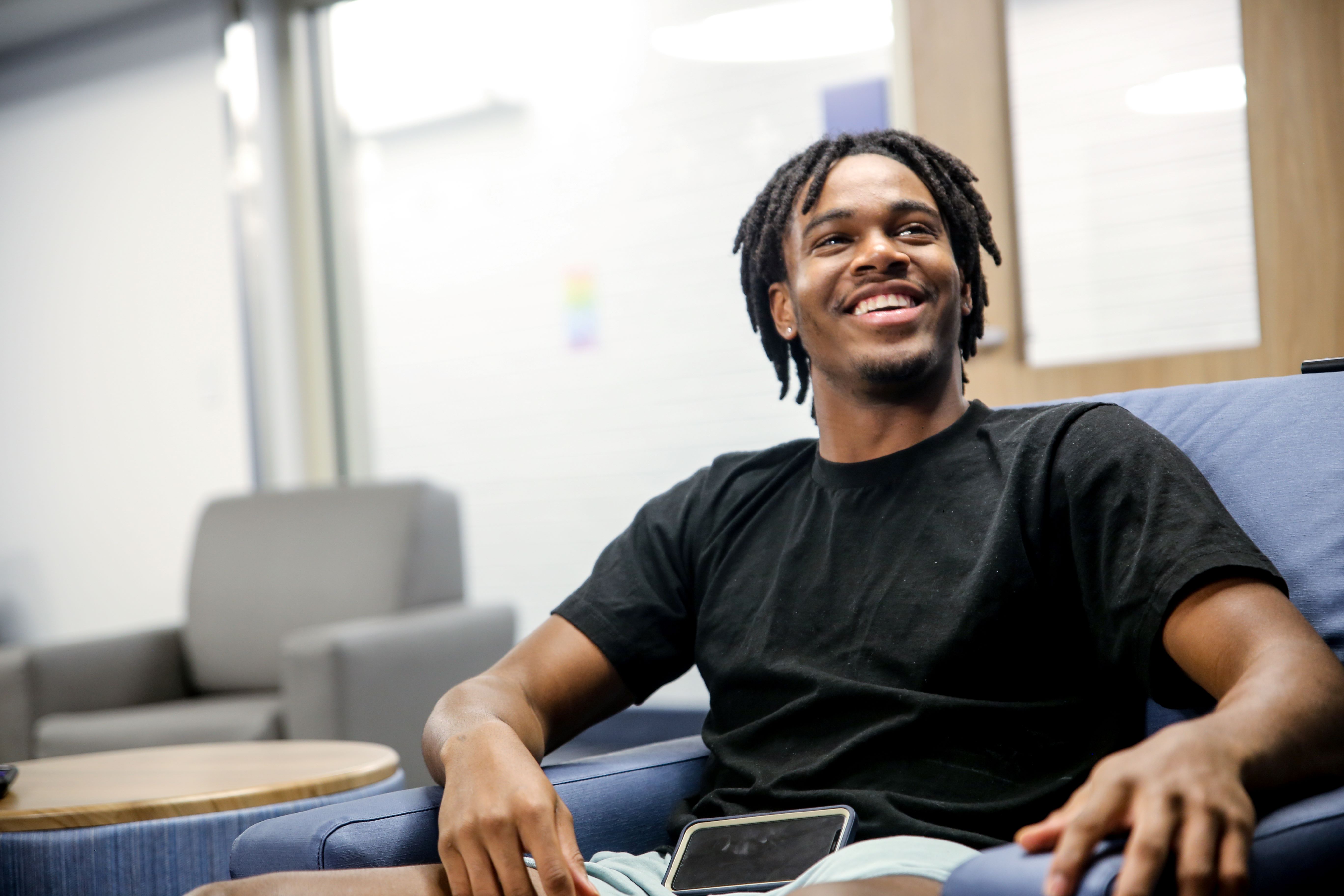 student smiling while sitting in dorm room