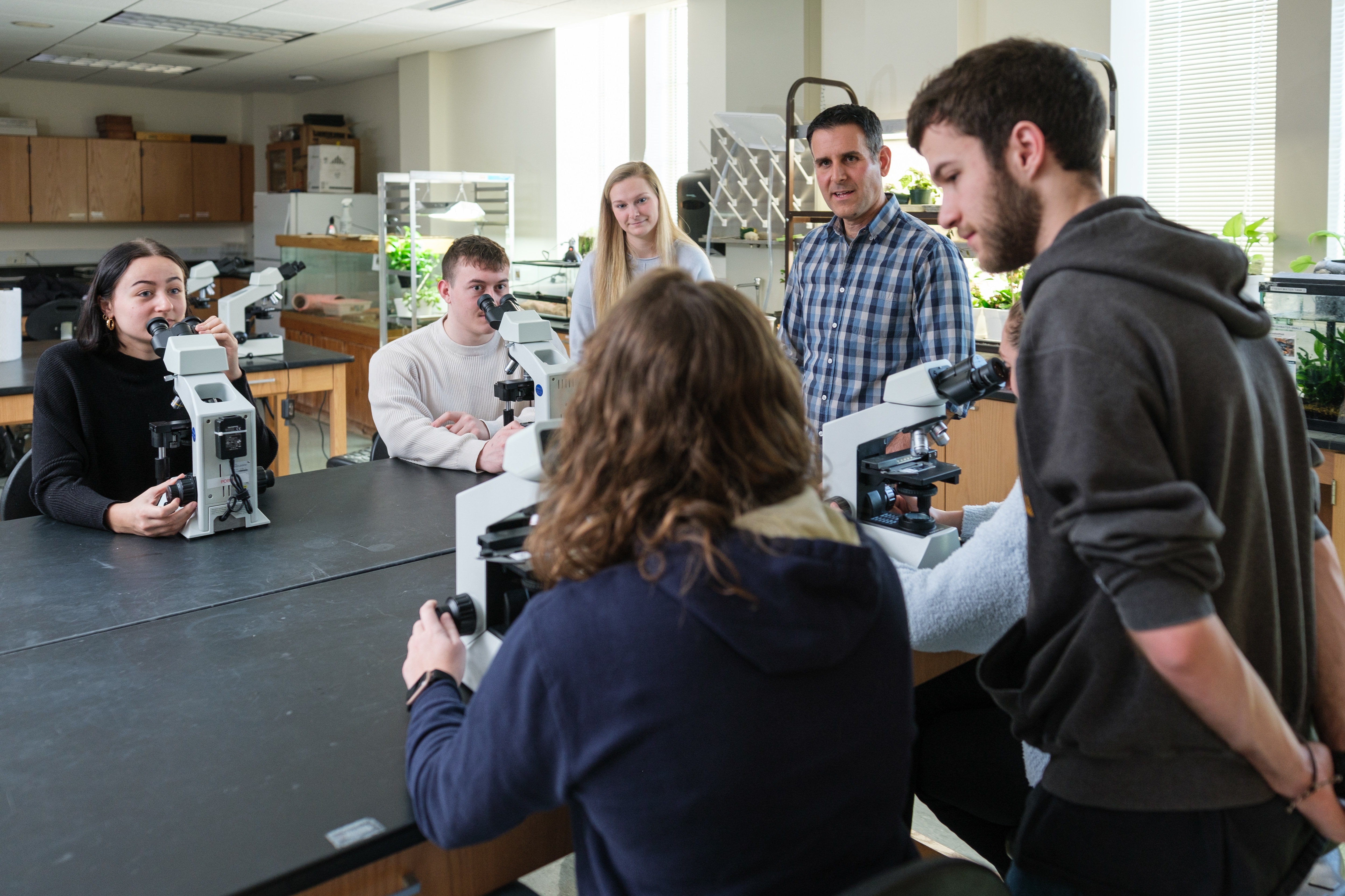 Students and science professor using microscopes