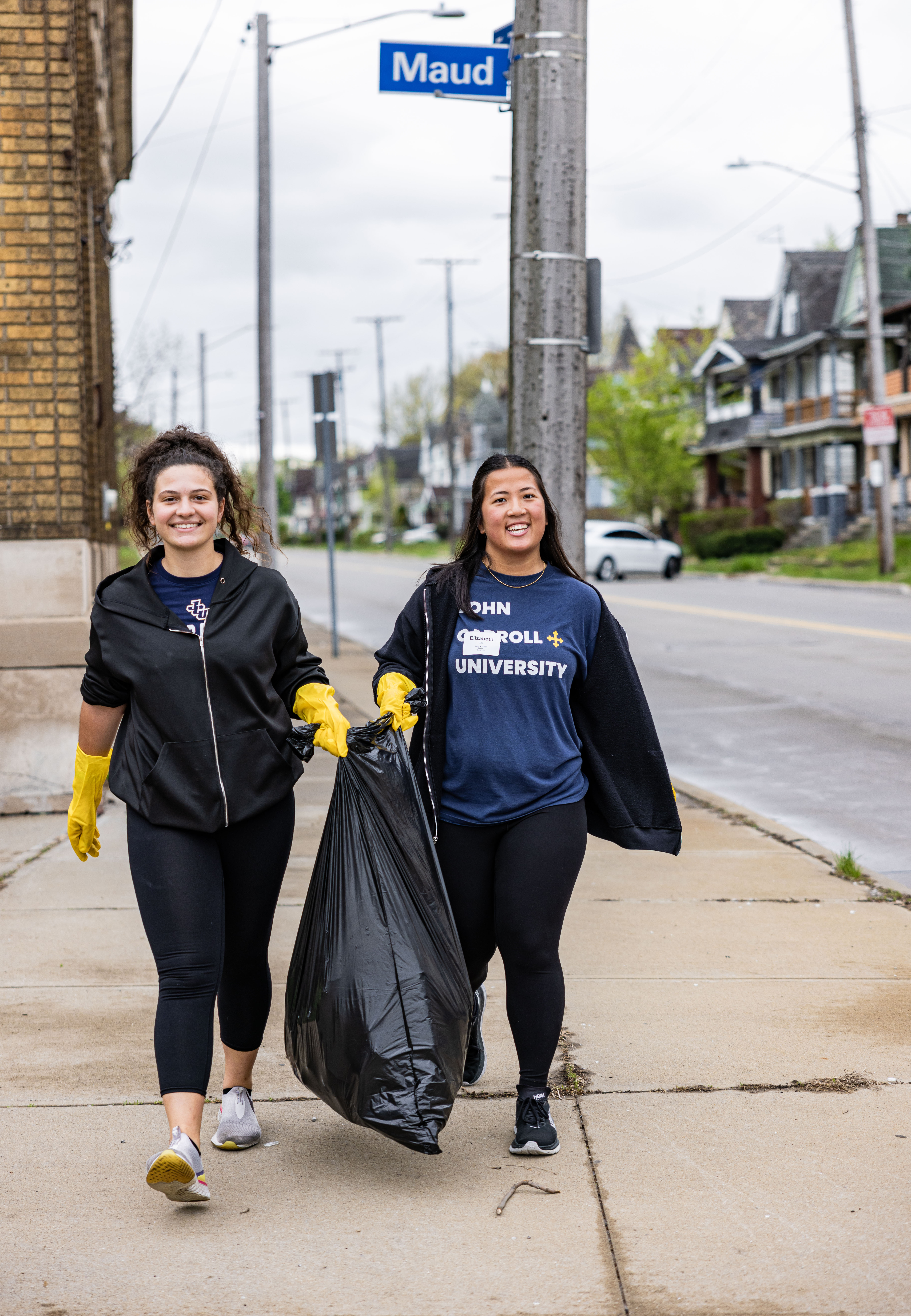 Two young girls carrying a bag full of trash after cleaning up a Cleveland neighborhood