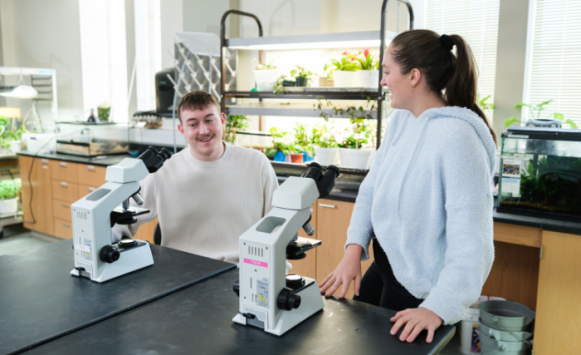 students talking with microscopes in biology lab