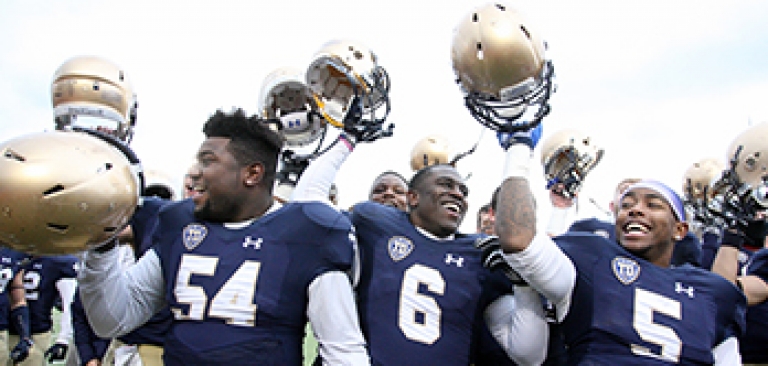 Football team members celebrating win, hoisting their helmets