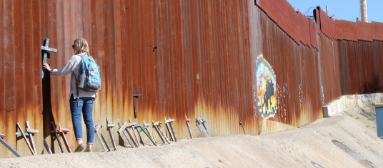 Girl standing at border wall.